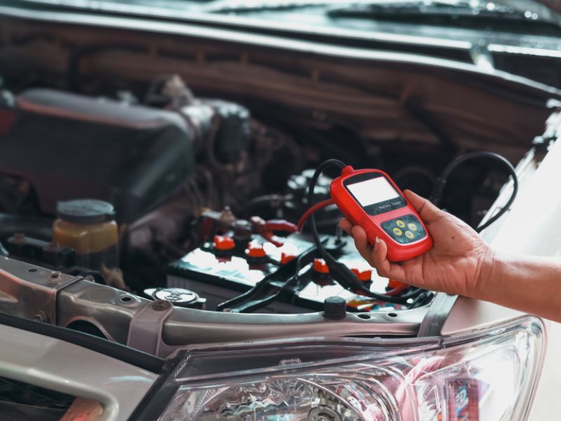 Technician checking a car battery with a diagnostic tool