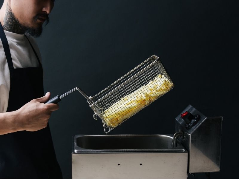 orang menggoreng kentang dengan fryer